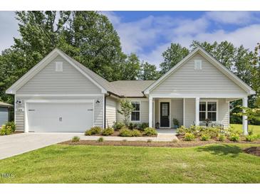Charming single-story home featuring a pristine front yard and an attached garage with a lovely front porch at 1304 Essex Skipper Way, Fuquay Varina, NC 27526