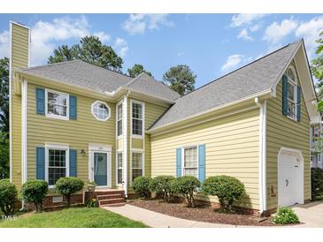 Charming home featuring a welcoming entrance, beautiful landscaping, and light yellow siding with blue shutters at 209 Woodstar Dr, Cary, NC 27513