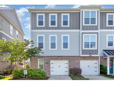 Stylish townhome featuring a brick facade, two-car garage, and neutral-toned siding for a modern look at 217 Jones Hill Rd, Holly Springs, NC 27540