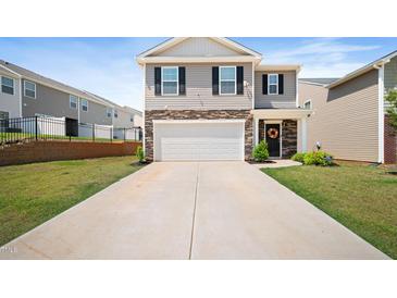 Charming two-story home features a two-car garage, stone accents, and well-manicured lawn at 2406 Lily Dr, Haw River, NC 27258