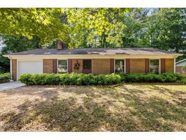 Charming brick home featuring manicured front yard with lush green hedges and brick-lined flowerbeds at 4119 Toroella St, Durham, NC 27704