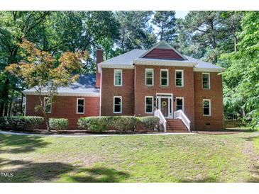 Traditional brick home with a landscaped front yard and inviting entrance with charming front lawn and mature trees at 5304 W Oaks Dr, Fuquay Varina, NC 27526