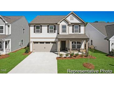 Charming two-story home featuring a two-car garage, covered porch, and beautifully landscaped front yard at 56 Mable Court # 20, Lillington, NC 27546