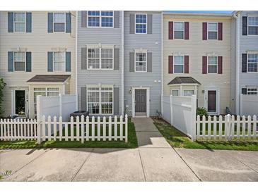 Charming townhouse featuring a welcoming entrance, well-maintained lawn, and classic white picket fence at 8630 Neuse Landing # 105, Raleigh, NC 27616