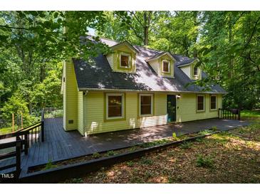 Inviting two-story home with a charming yellow exterior and spacious deck, nestled among lush green trees at 106 Redbud, Pittsboro, NC 27312