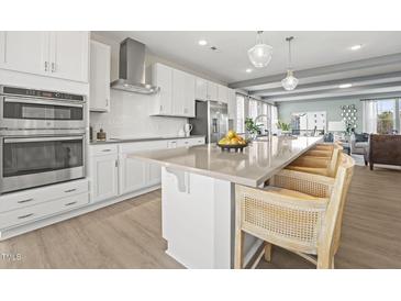 Modern kitchen featuring white cabinets, stainless steel appliances, and a large center island with bar seating at 1247 Shaw View Alley # 201, Raleigh, NC 27601