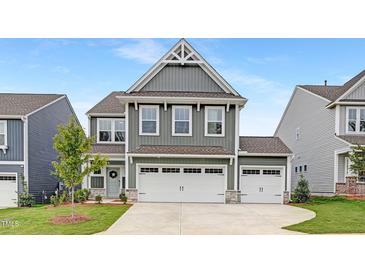 Charming two-story home featuring a three car garage, manicured lawn, and modern architectural details at 140 Summer Mist Ln # 159, Clayton, NC 27527