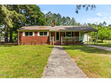 Charming brick home featuring a covered porch, mature trees, and a well-manicured lawn at 1709 Whitfield Ave, Rocky Mount, NC 27801