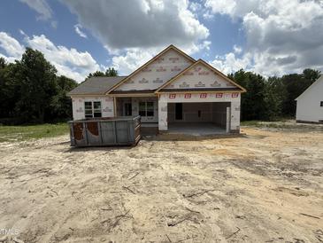 New construction home with an open garage, surrounded by a partially cleared lot, under a partly cloudy sky at 2760 Rains Mill Rd, Princeton, NC 27569