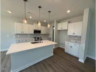 Spacious kitchen features a large island, stainless steel appliances, and ample white cabinetry at 293 Gregory Village Dr, Lillington, NC 27546