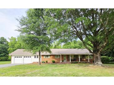 Charming brick ranch-style home with attached garage, mature trees and a well-manicured lawn at 3669 W Greensboro Chapel Hill Rd, Liberty, NC 27298