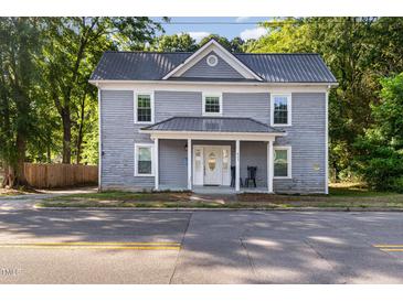 Charming two-story home featuring a metal roof and inviting front porch, surrounded by mature trees at 411 E Green St, Franklinton, NC 27525