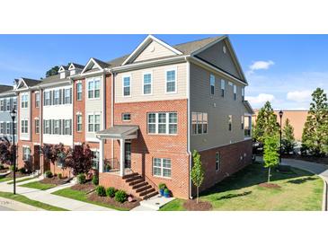 Stunning three-story townhome featuring a brick facade, welcoming entrance, and manicured landscaping at 518 Toran Dr, Wake Forest, NC 27587