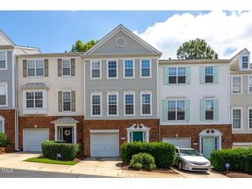 Charming townhome exterior featuring brick accents, a one-car garage, and colorful doors at 7244 Galon Glen Rd, Raleigh, NC 27613