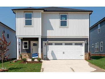 Charming two-story home featuring a white garage door, gray accents, and a well-maintained lawn at 832 Ottawa Dr, Garner, NC 27529