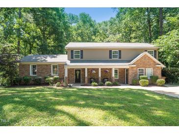 Charming two-story home with stone and siding, a covered porch, and a large manicured front yard at 1015 Manchester Dr, Cary, NC 27511
