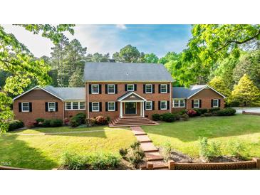 Charming brick two-story home with manicured lawn, mature trees, and inviting walkway at 12088 Burlington Rd, Hurdle Mills, NC 27541