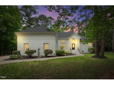 Charming white brick home with manicured landscaping and walkway to the front door at 12301 Hardee Rd, Raleigh, NC 27614
