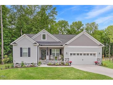 Charming home featuring stone accents, a well-manicured lawn, and an attached two-car garage at 176 Lowery Ln, Benson, NC 27504