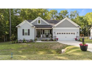 Charming single-story home featuring a landscaped yard, cozy front porch with rocking chairs and a two-car garage at 176 Lowery Ln, Benson, NC 27504