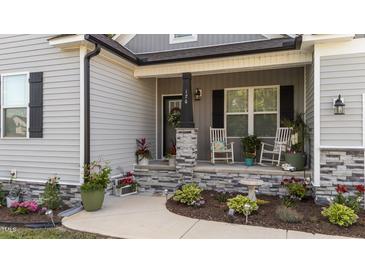 Inviting front porch with rocking chairs and stone accents, surrounded by colorful plants and charming decor at 176 Lowery Ln, Benson, NC 27504