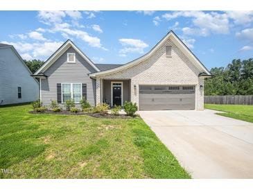 Charming one-story home with a manicured lawn, two-car garage, and brick and vinyl siding at 1828 Wellspring Ct, Graham, NC 27253