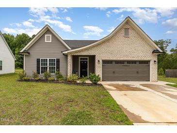Charming single-story home featuring a mix of brick and vinyl siding, a two-car garage, and well-maintained landscaping at 1828 Wellspring Ct, Graham, NC 27253