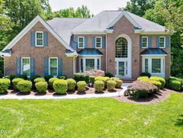 Beautiful brick home featuring manicured landscaping, blue shutters, and a grand two-story entrance at 225 Midenhall Way, Cary, NC 27513