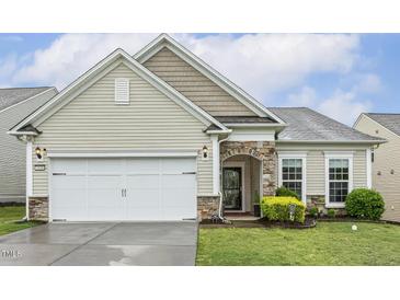 Charming home exterior featuring stone accents, manicured lawn, and an attached two-car garage at 2410 Kinglass Dr, Fuquay Varina, NC 27526