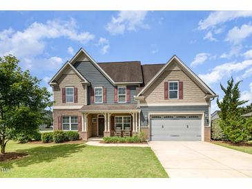 Charming two-story home featuring a manicured lawn, attached garage, and inviting front porch at 2507 Belvinwood Dr, Fuquay Varina, NC 27526