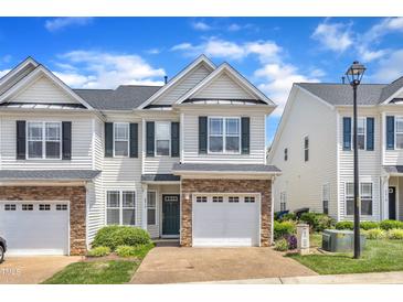 Charming townhome featuring stone accents, a one-car garage, and lush landscaping at 2513 Asher View Ct, Raleigh, NC 27606