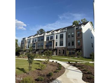 Beautiful townhome exterior with well-manicured lawn and sidewalk leading to the front entrances under a blue, partly cloudy sky at 3104 Kempthorne Rd # 48, Cary, NC 27519