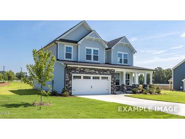 Charming two-story home featuring stone accents, a two-car garage, a welcoming front porch, and a well-manicured lawn at 444 Golden Dragonfly St, Wake Forest, NC 27587