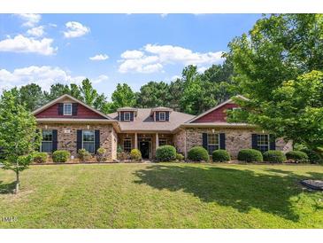 Charming brick home featuring a lush green lawn and mature landscaping at 46 Spring Haven Ln, Willow Springs, NC 27592