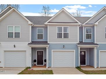 Charming townhome exteriors featuring light blue and grey siding, attached garages, and inviting front doors at 882 John St, Clayton, NC 27520