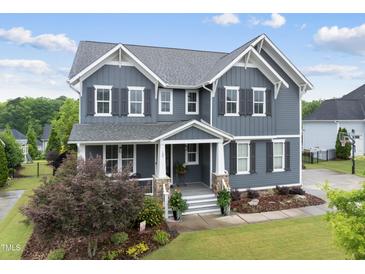 Charming two-story home with gray siding, landscaped yard, and a welcoming front porch at 109 Big Timber Path, Holly Springs, NC 27540