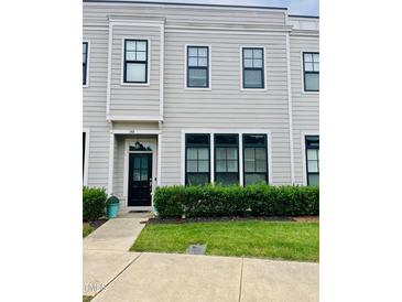 Charming townhome with gray siding, black trim, manicured lawn, and sidewalk at 142 Philips Sq, Chapel Hill, NC 27516