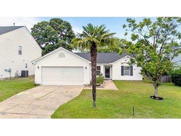 Charming single-Gathering home with attached garage and manicured front lawn featuring mature palm tree at 1725 E Honey Springs Ave, Fuquay Varina, NC 27526