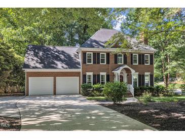 Charming brick home featuring an attached two car garage and well-manicured landscaping at 2125 Oakcrest Ct, Raleigh, NC 27612