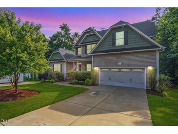 Charming two-story home featuring a well-manicured lawn and a two-car garage on a tree-lined lot at 68 Tanners Way, Clayton, NC 27527