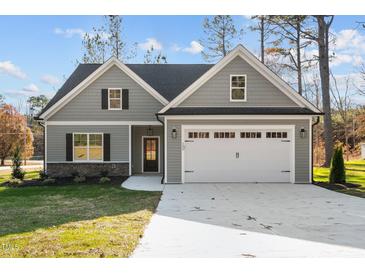 Charming home featuring a two-car garage, stone accents, and a well-maintained lawn at 100 Carol Cir # 17, Louisburg, NC 27549