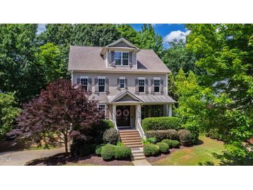 Charming two-story home with landscaped yard, flowering tree, and covered entry featuring beautiful decorative wreaths at 101 Eden Glen Dr, Holly Springs, NC 27540