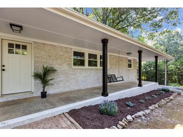 Inviting front porch with a swing, charming brick accents, and a well-manicured landscape for a relaxing outdoor space at 1302 Buffaloe Rd, Garner, NC 27529
