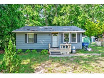 Charming single-story home with blue siding and a quaint front porch, surrounded by lush greenery at 230 Parkland Rd, Raleigh, NC 27603