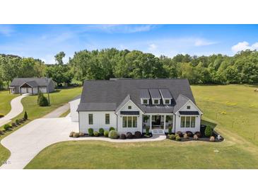 Stunning aerial view of a modern farmhouse featuring a black roof and lush green lawn at 2408 Eddie Howard Rd, Willow Springs, NC 27592