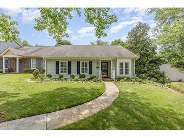 Charming single-story home featuring manicured lawn, flower beds, and a curved walkway leading to the front door at 2617 Cottage Cir, Raleigh, NC 27613