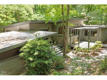 Contemporary home featuring a flat roof, complemented by beautiful landscaping and natural wooded surroundings at 2713 Mcdowell Rd, Durham, NC 27705