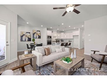 Modern living room featuring neutral tones, stylish furniture, and an open layout connecting to the kitchen at 3924 Well Fleet Dr, Fuquay Varina, NC 27526