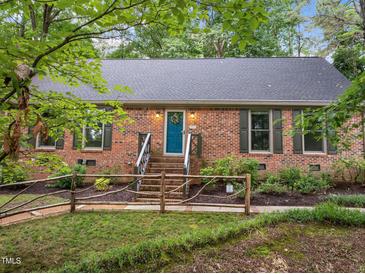 Charming brick home featuring a beautifully landscaped front yard and a vibrant teal front door at 6925 Valley Lake Dr, Raleigh, NC 27612