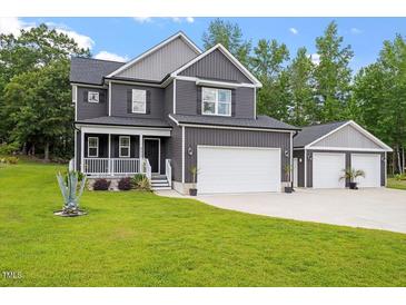 Charming two-story home with a well-manicured lawn, two car garage, and inviting front porch with white picket fence at 852 Cokesbury Park Lane Ln, Fuquay Varina, NC 27526